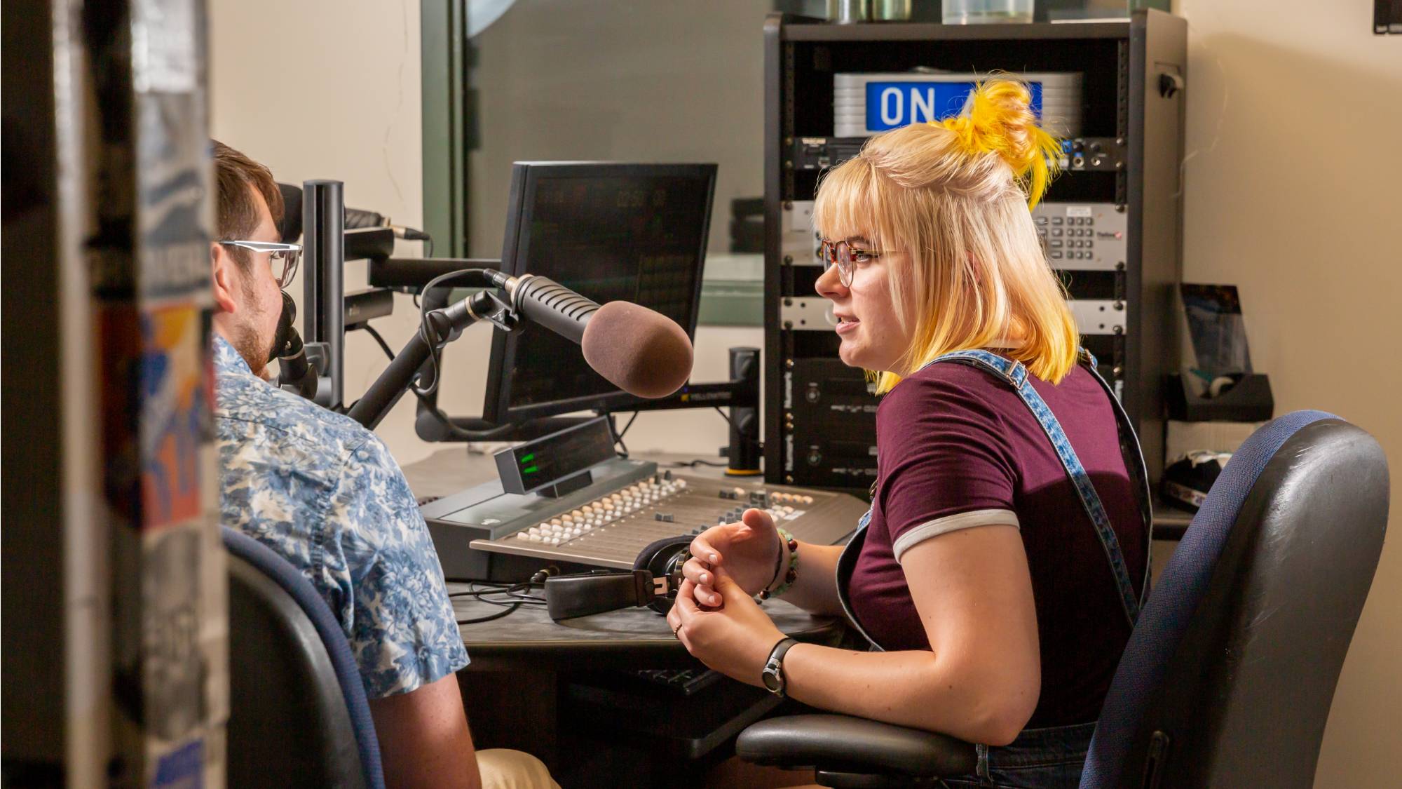 Student talking with student at radio station control board